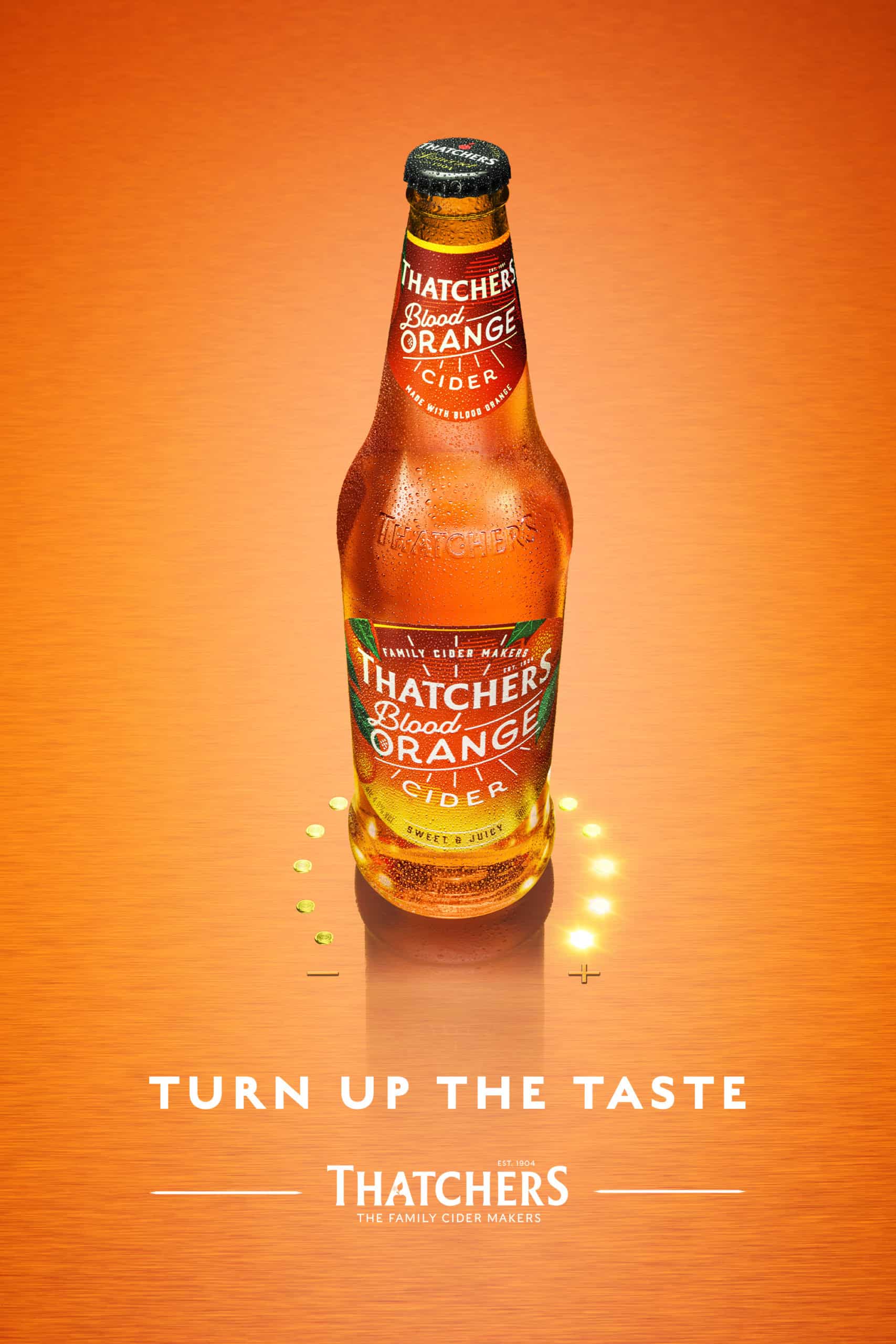 Single bottle of a chilled Thatchers Blood Orange Cider surrounded by lights and showing liquid droplets. Shot by Drinks Photographer Jonathan Knowles in his London studio.